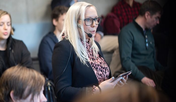 Moderator med headset-mikrofon håller i iPad och talar vid event på Goto10.