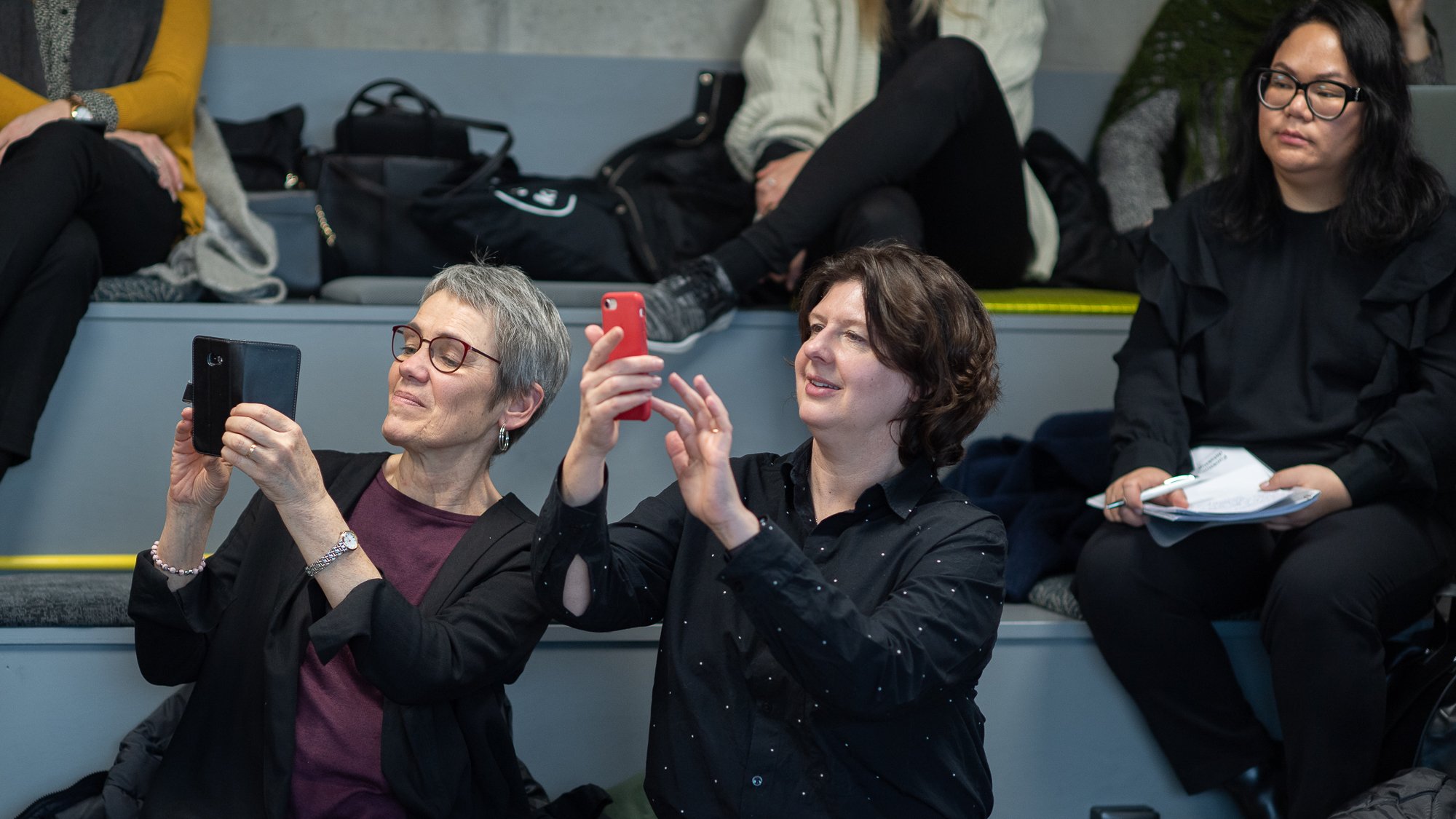 Publik vid event på Goto10. Två kvinnor i publiken fotograferar scenen med varsin mobiltelefon.